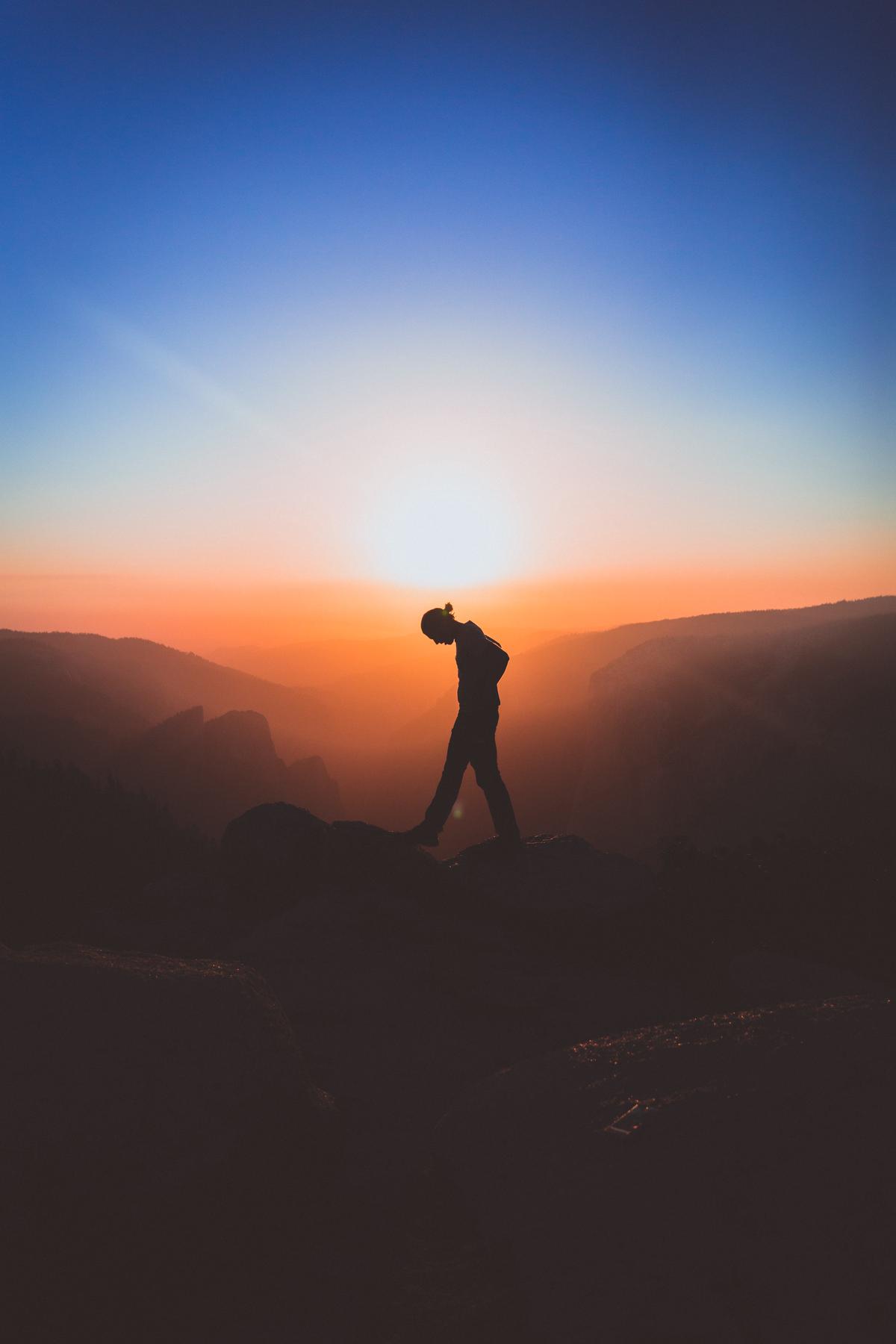 An image depicting a person standing on a mountain peak, symbolizing self-discovery and reaching one's potential.